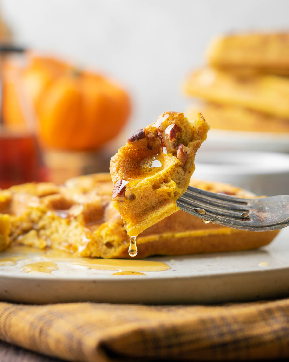 Closeup of a bite of waffle with syrup dripping off.