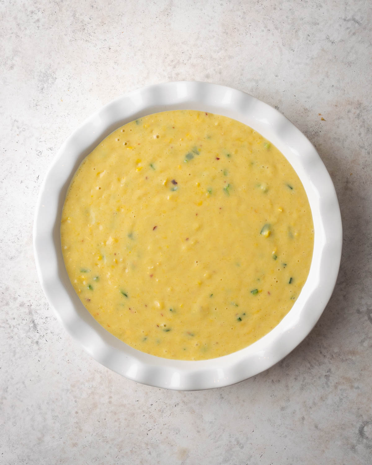 Unbaked corn casserole in a white baking dish.