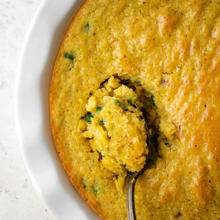 A spoon of gluten free corn casserole being served from a dish.