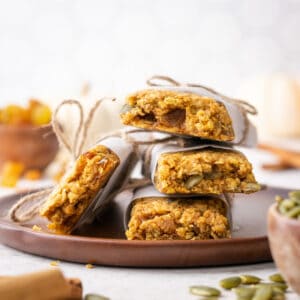 A stack of pumpkin granola bars on a wood plate.