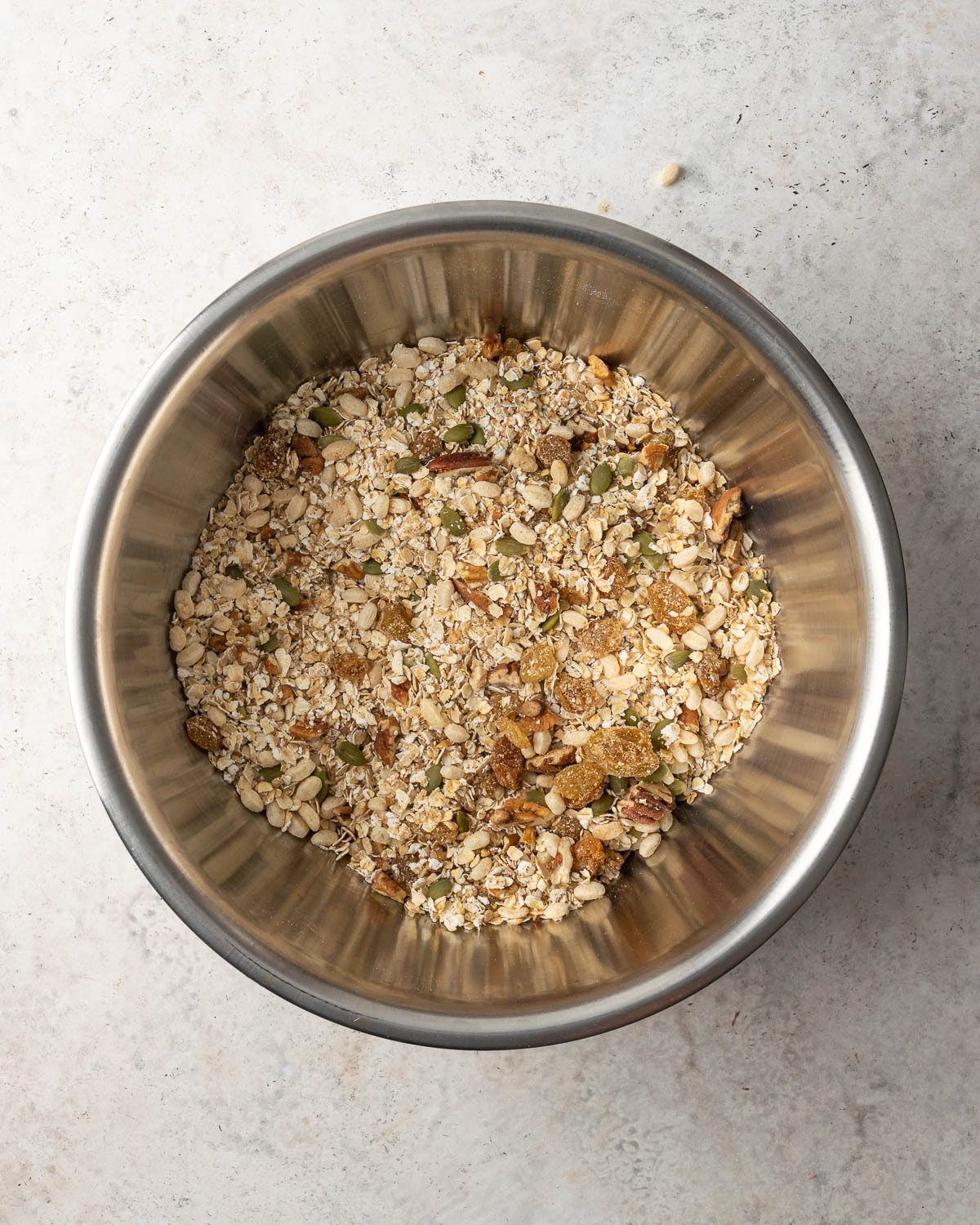 Dry ingredients for pumpkin granola bars mixed in a large metal bowl.