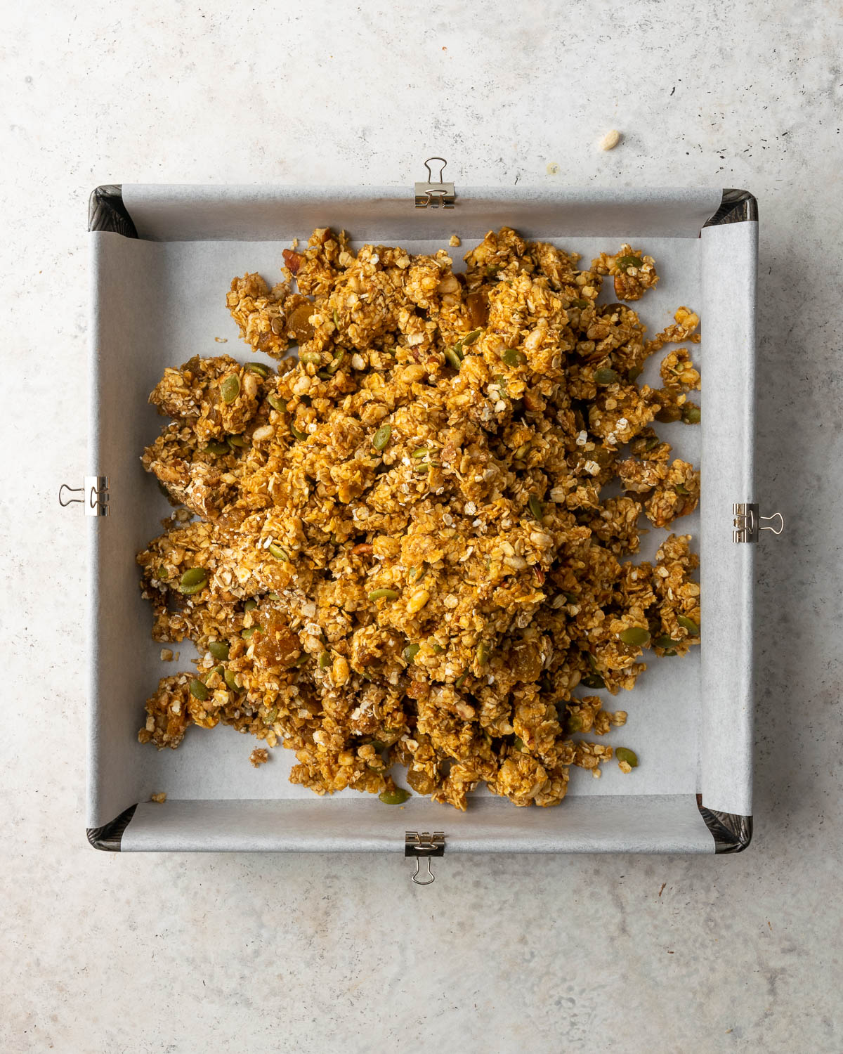 Granola bar mixture poured into a square baking pan.