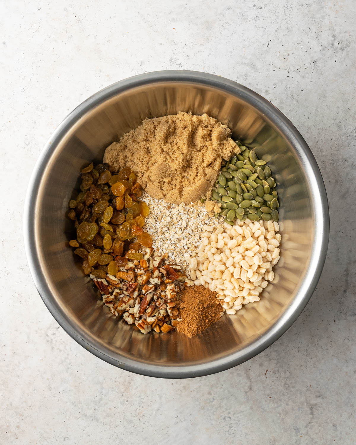 Ingredients for pumpkin granola bars in a large metal bowl.