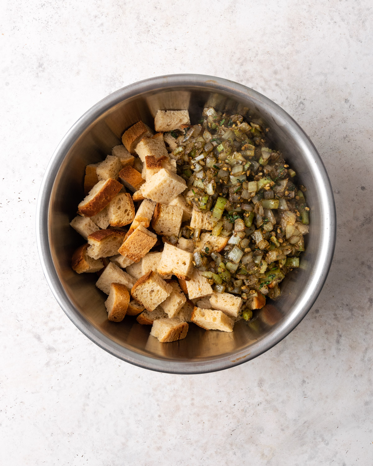 Breadcrumbs and seasoning being combined in a metal bowl.