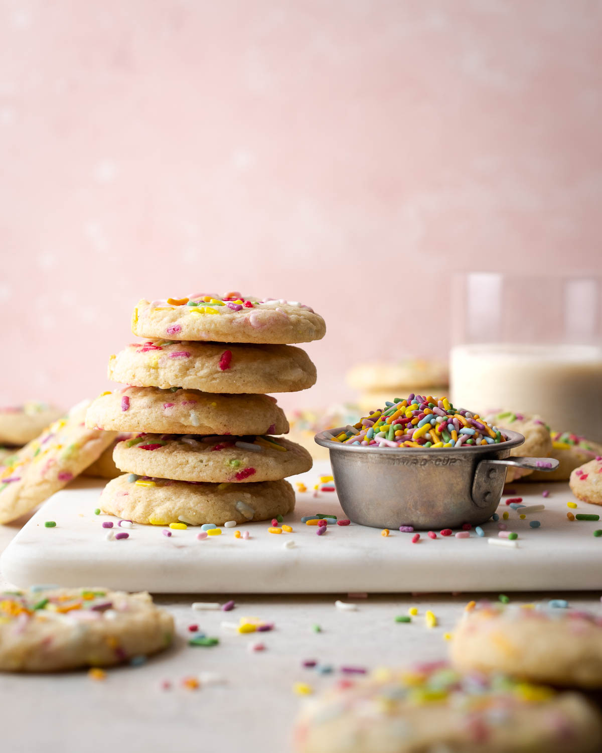 A stack of gluten free sugar cookies on a white cutting board.