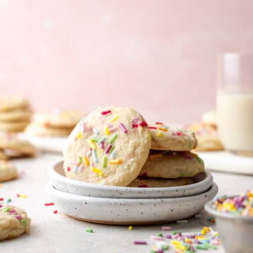 A stack of gluten free sugar cookies on a white plate.