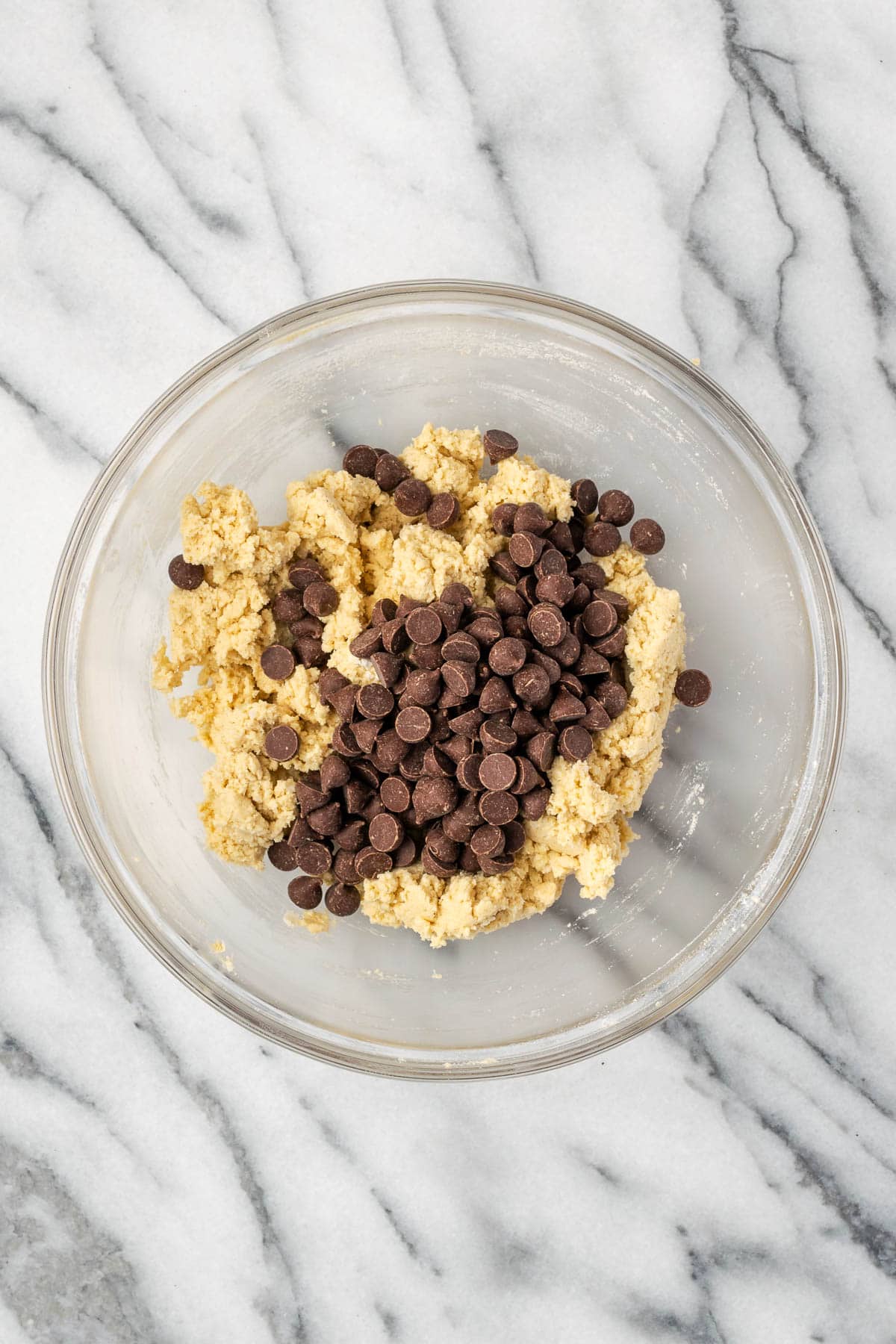 Chocolate chips being stirred into the gluten free cookie dough. 