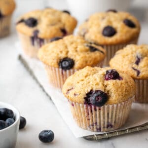 A batch of freshly baked banana blueberry muffins on a cooling rack.