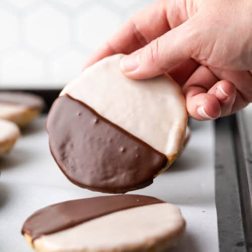 A black and white cookie being picked up from the baking sheet.