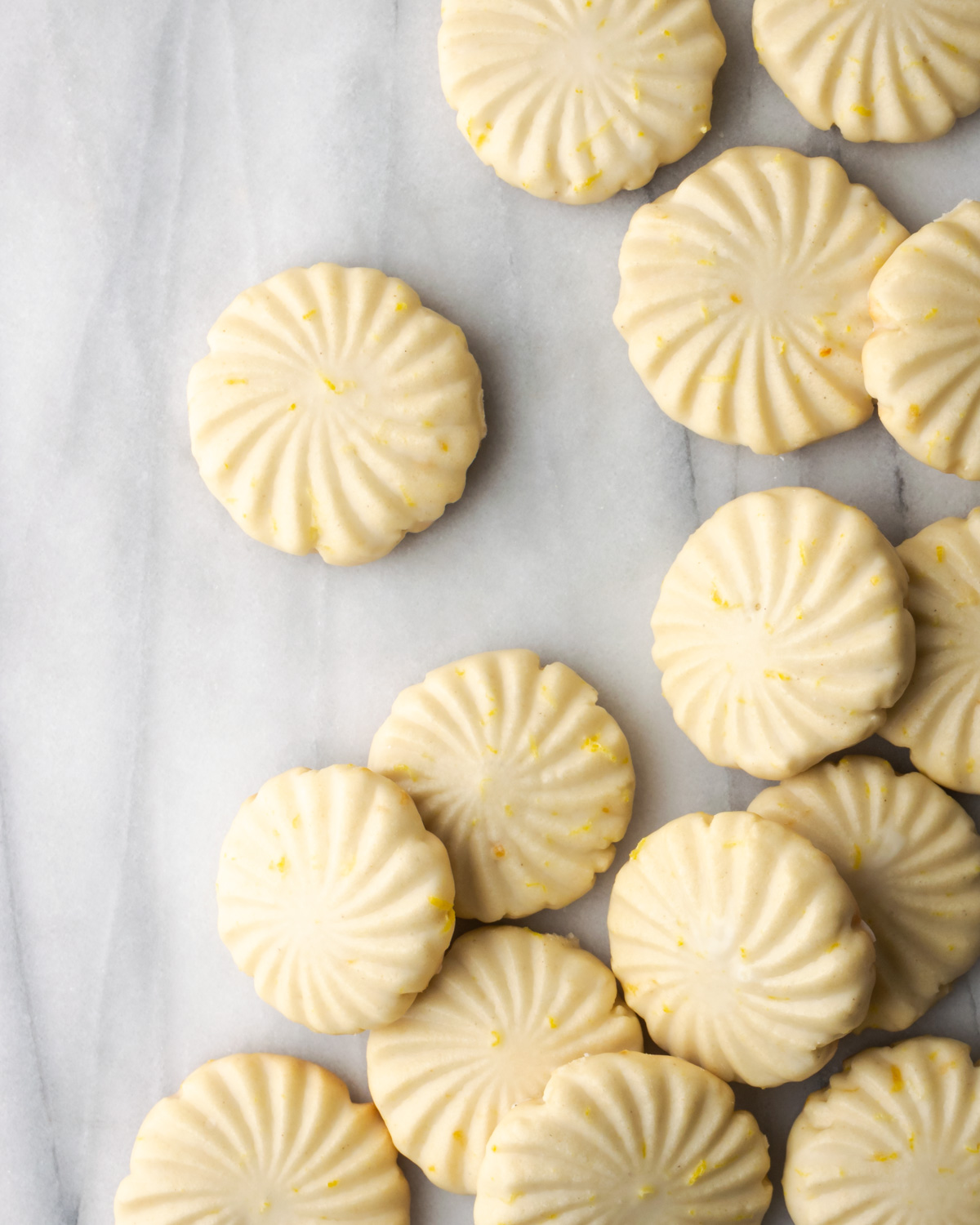 Lemon cookies scattered on a marble counter.