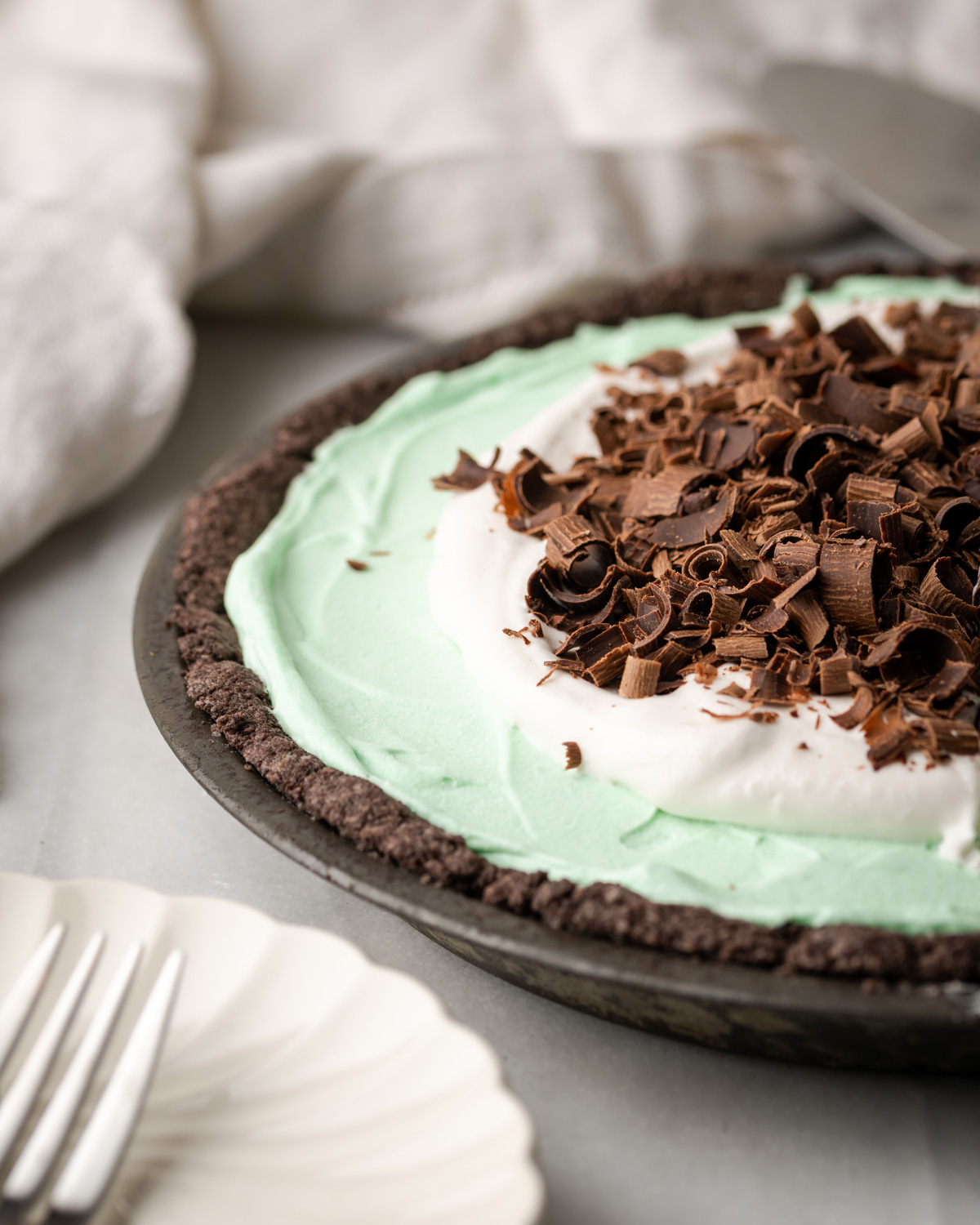 A mint pie with whipped cream and chocolate curls on top.