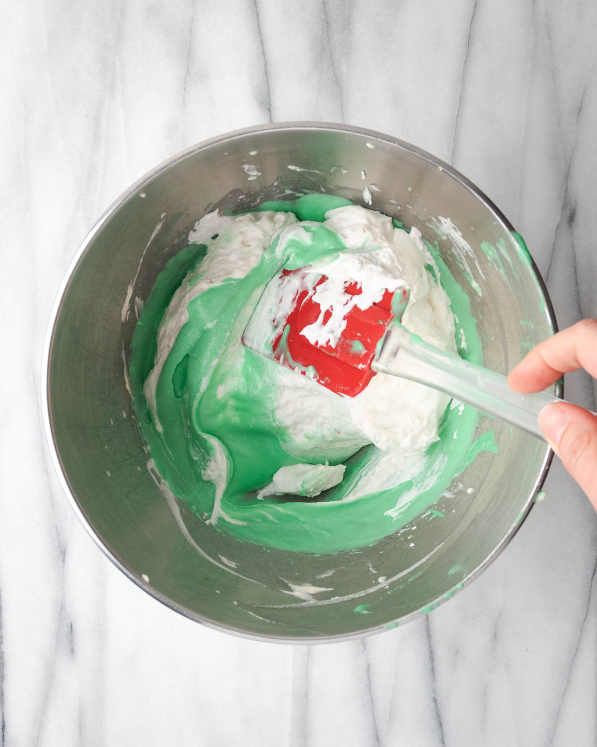 Spatula folding whipped cream into green pie filling.
