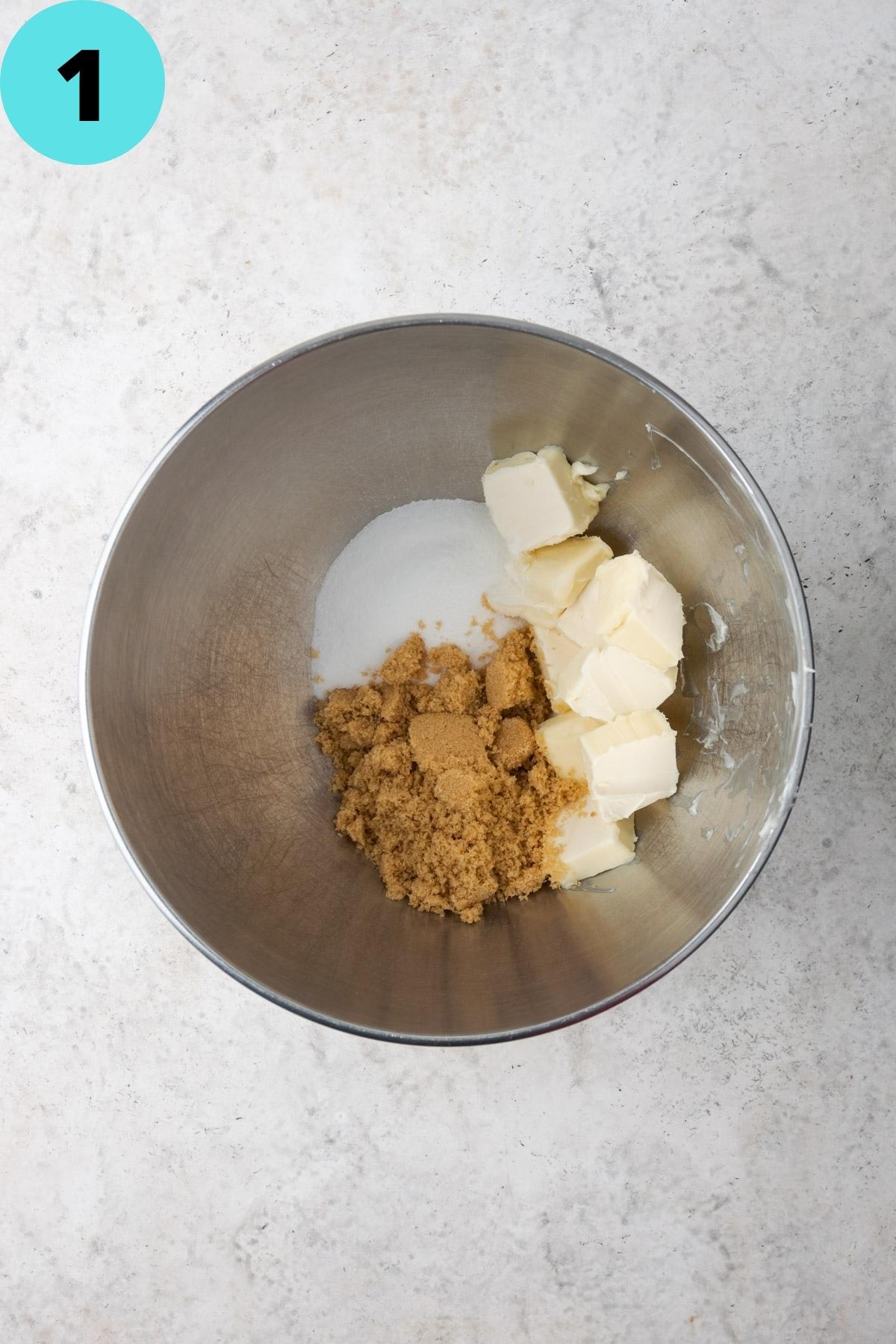 Butter and sugars in a metal mixing bowl.