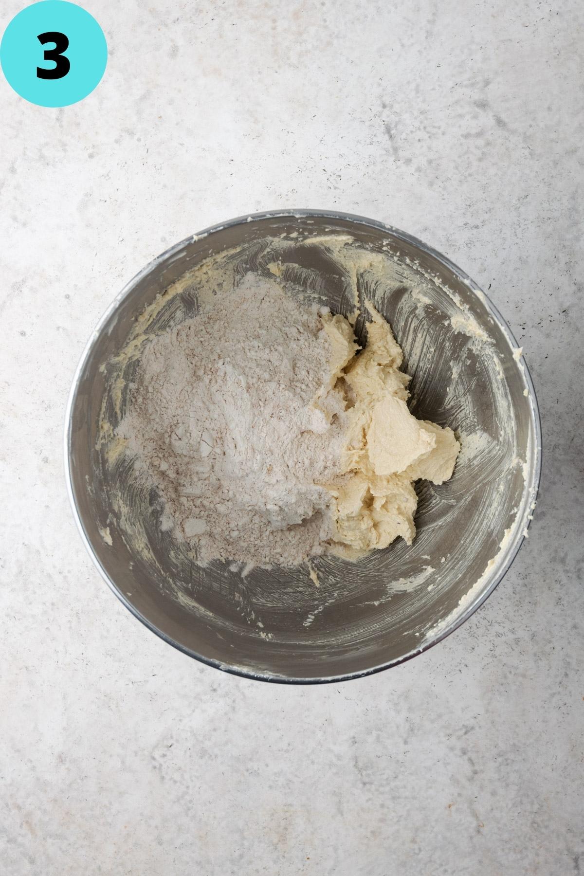 Creamed butter and sugar with gluten free flour added to a metal mixing bowl. 