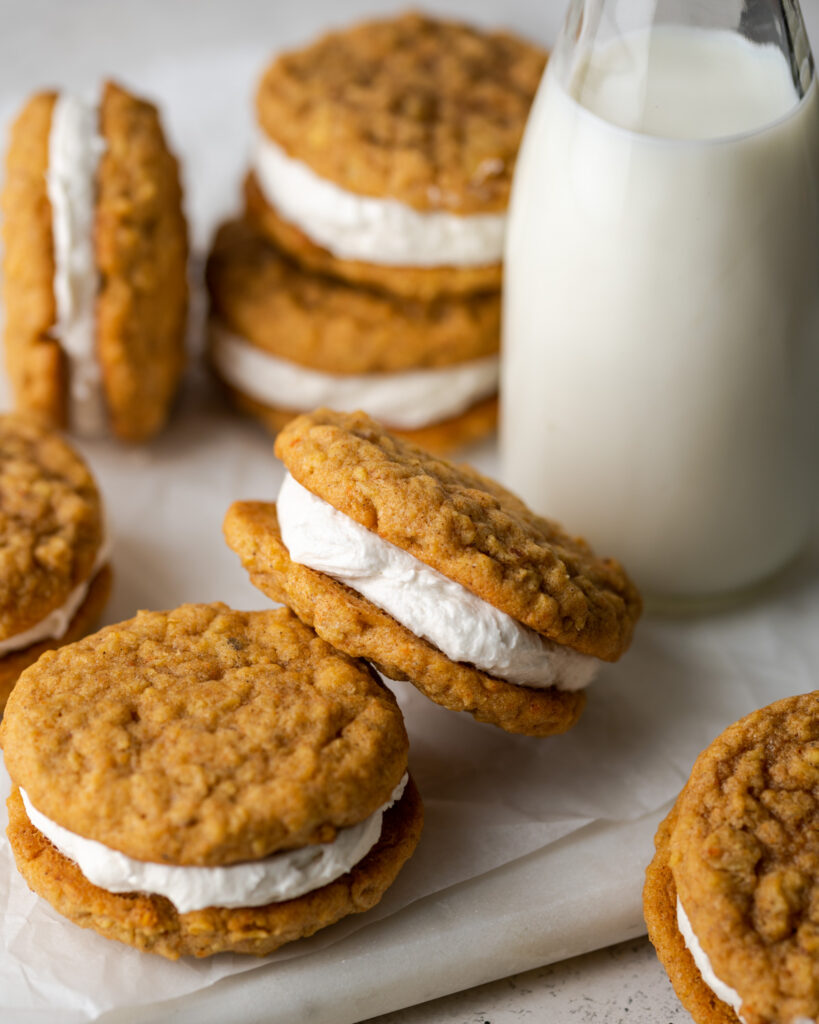 Carrot Cake whoopie pies and a jar of milk on a marble cutting board.