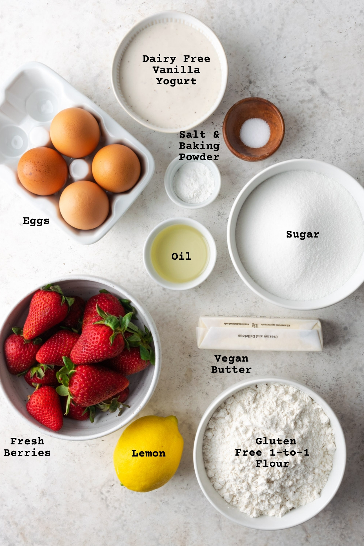 Ingredients for gluten free strawberry lemon yogurt cake on a white table.