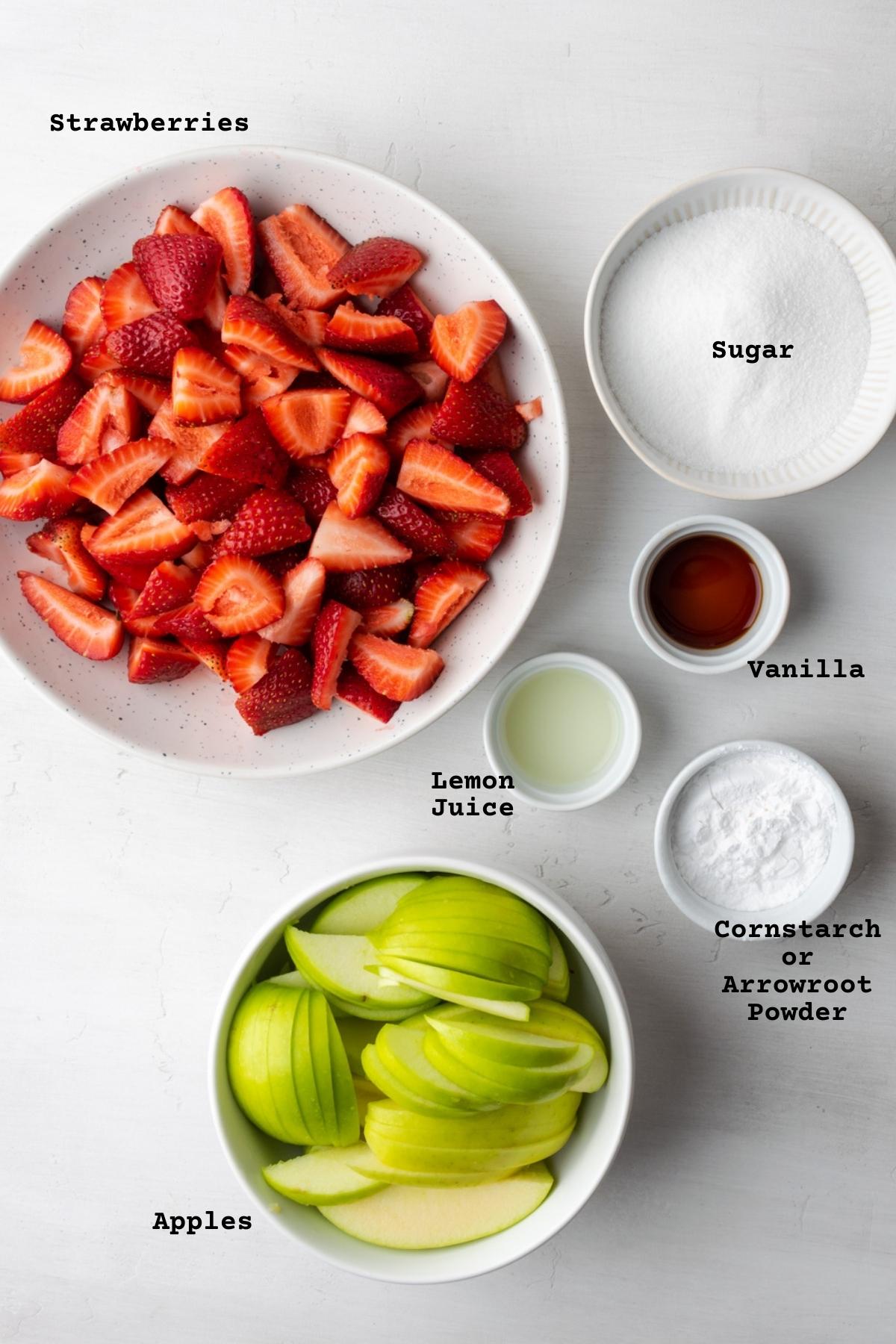 Ingredients for strawberry apple pie filling on a white table.