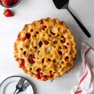 A freshly baked strawberry apple pie on a white table.
