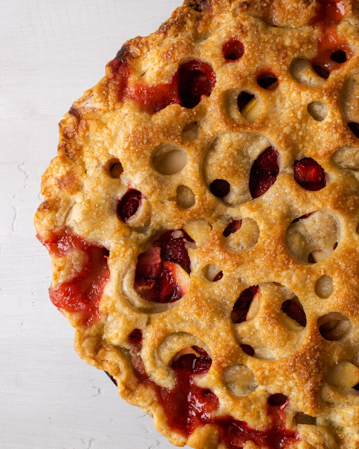 A freshly baked strawberry apple pie with fruit juices running out of the top.