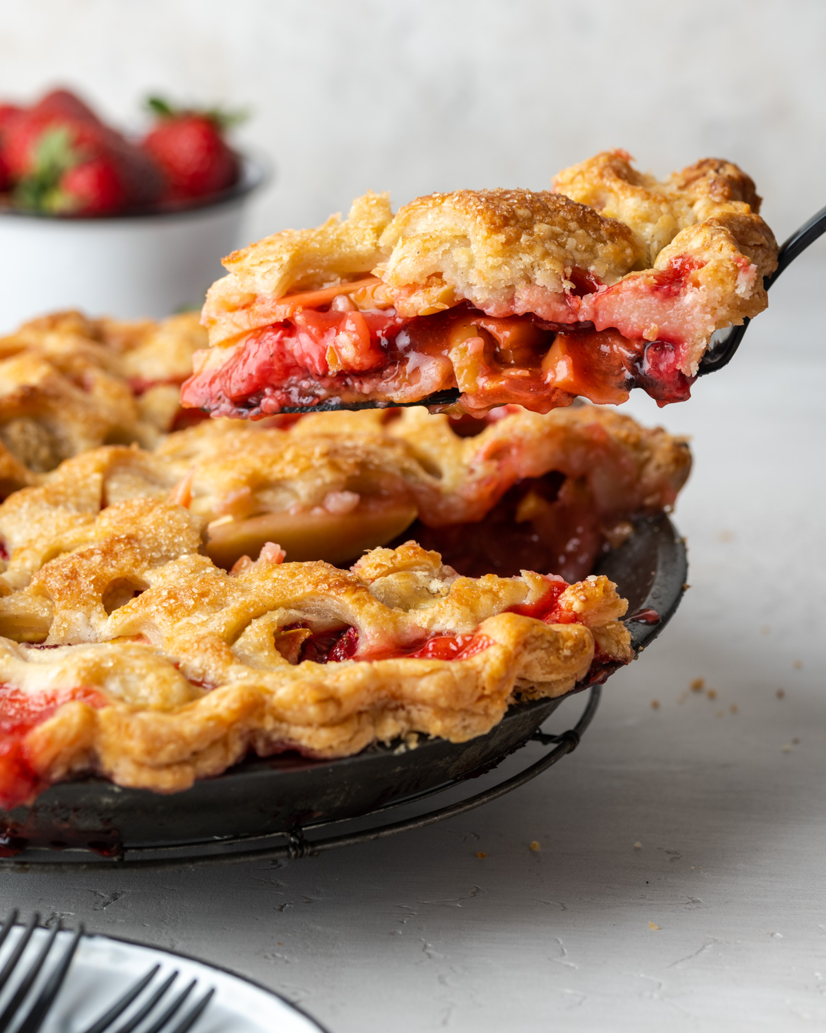 A slice of strawberry apple pie being removed from the pan.