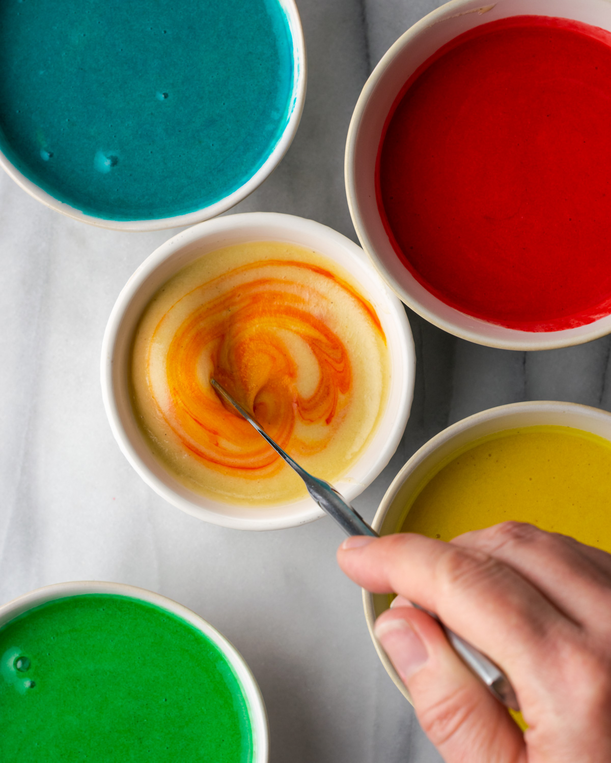 Small bowls of cake batter with food coloring added.