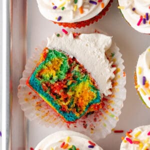 A cut open tie dye cupcake topped with buttercream frosting.
