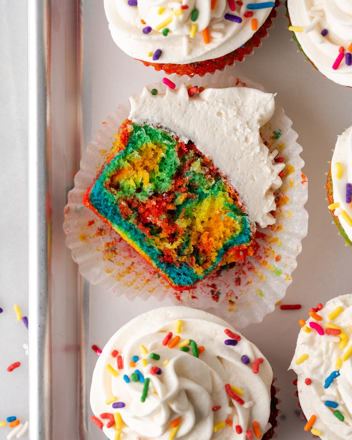 A cut open tie dye cupcake topped with vanilla frosting.