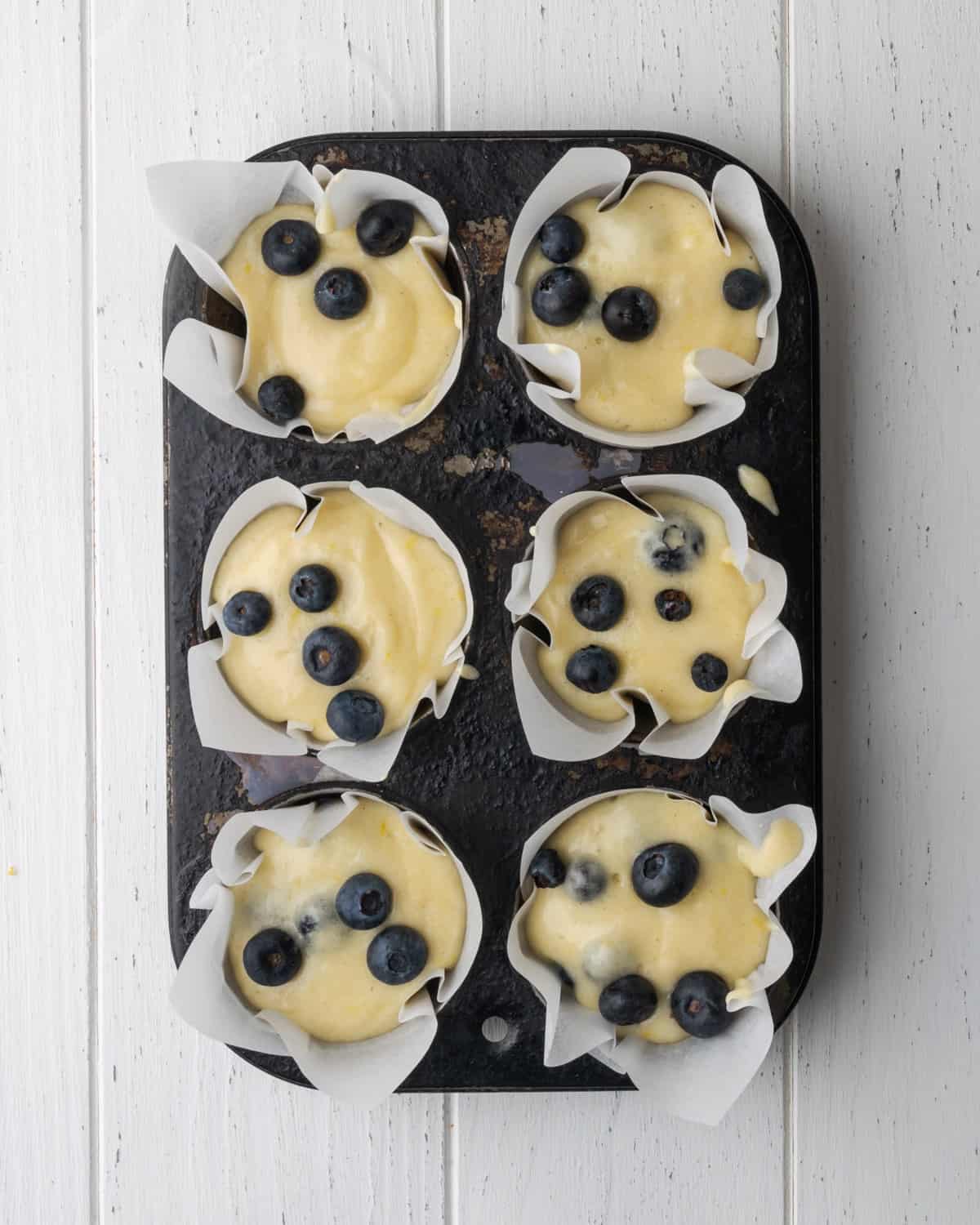 Unbaked muffin batter portioned into a 6 cup muffin tin.