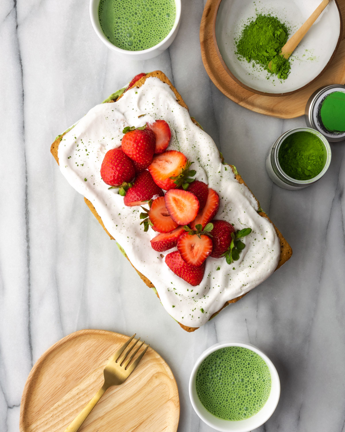 Overhead view of strawberry matcha cake on a marble table.