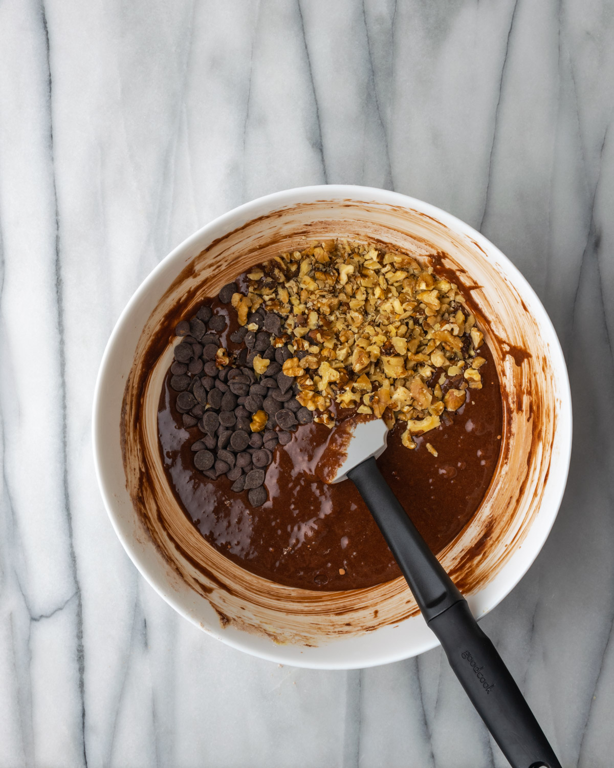 Walnuts being mixed into a bowl of brownie batter.