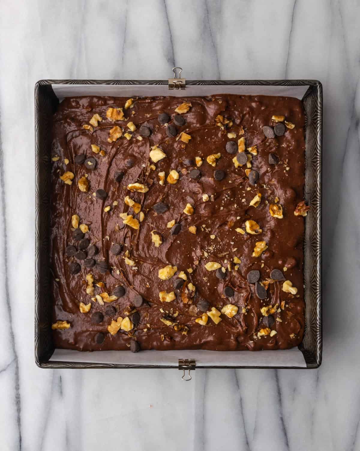 Unbaked brownie batter in a square baking pan.