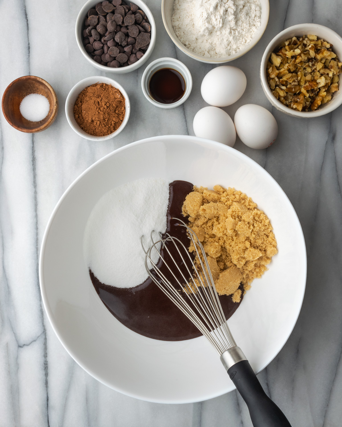 Sugar and melted chocolate being whisked in a bowl.