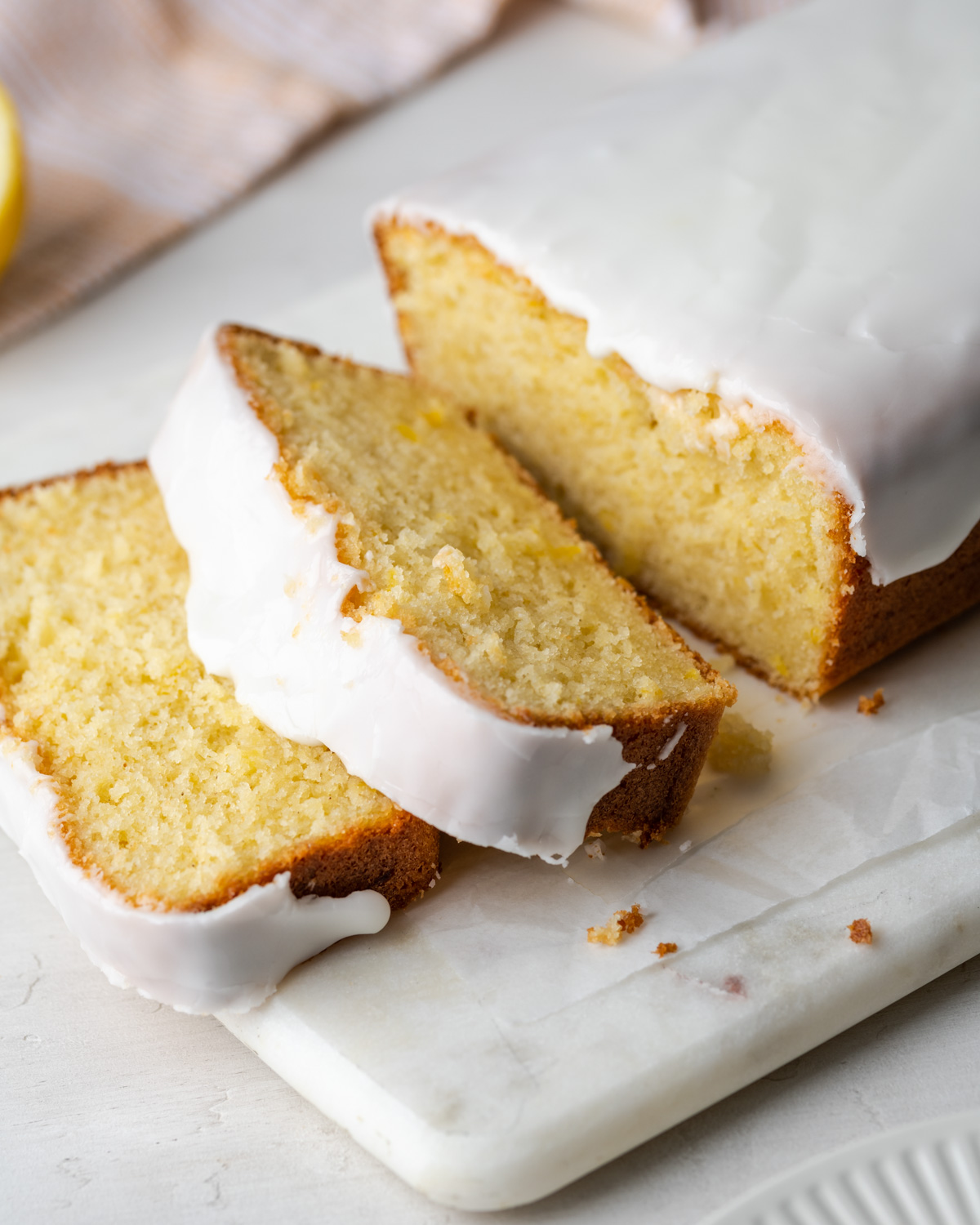 Closeup of slices of lemon loaf cake on a white cutting board.