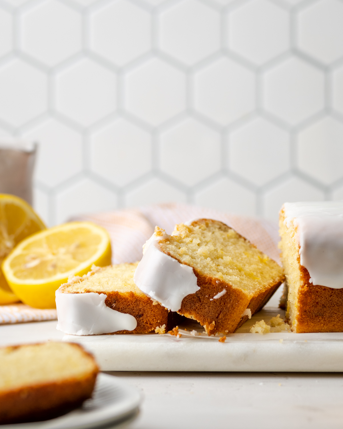 Sliced gluten free lemon loaf cake on a white cutting board.