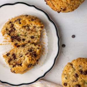 A sliced open zucchini chocolate chip muffin on a white plate.