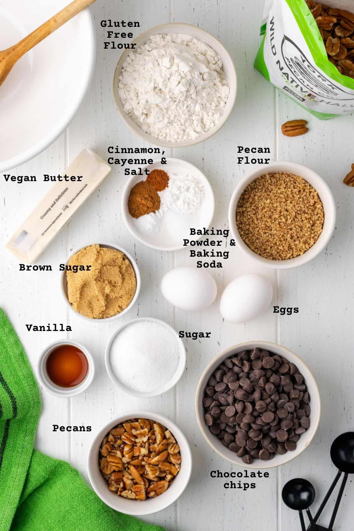 Ingredients for pecan chocolate chip cookies on a white wooden table.