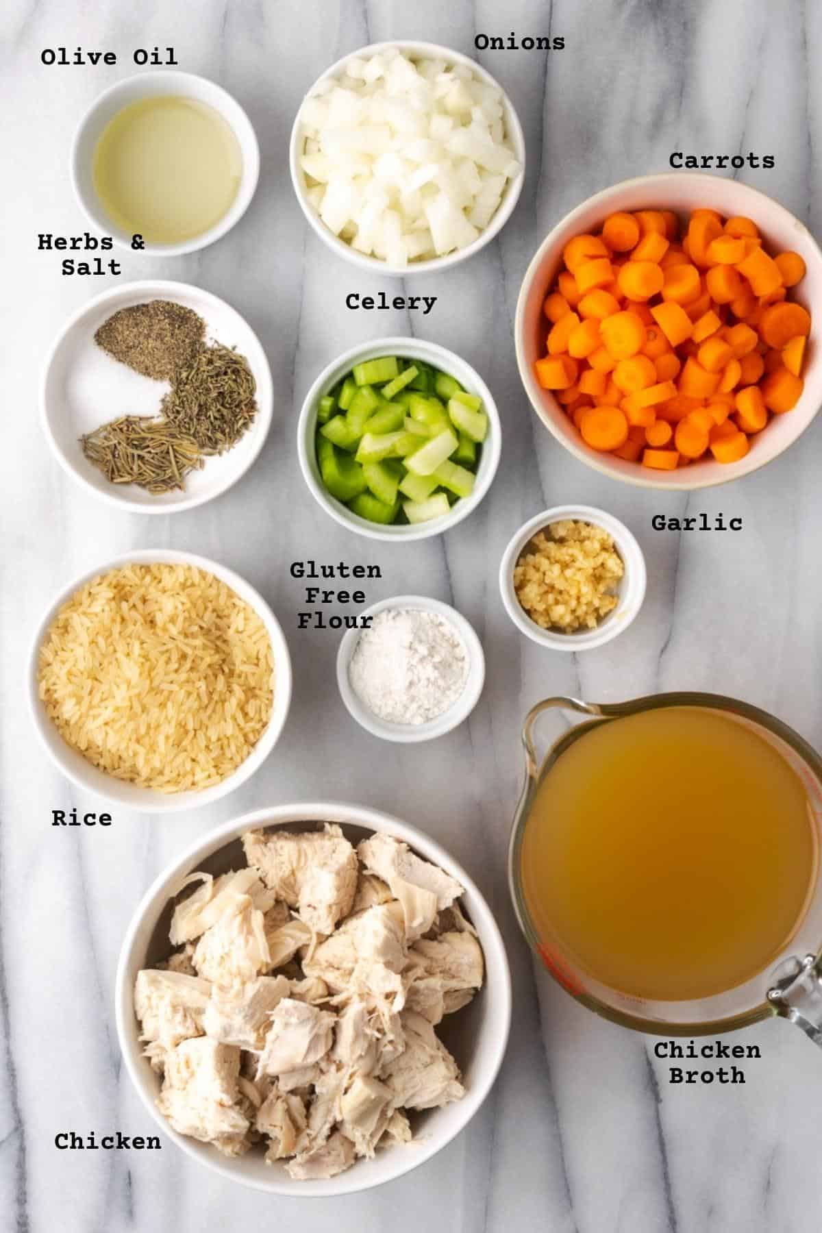 Ingredients for chicken and rice soup on marble table.
