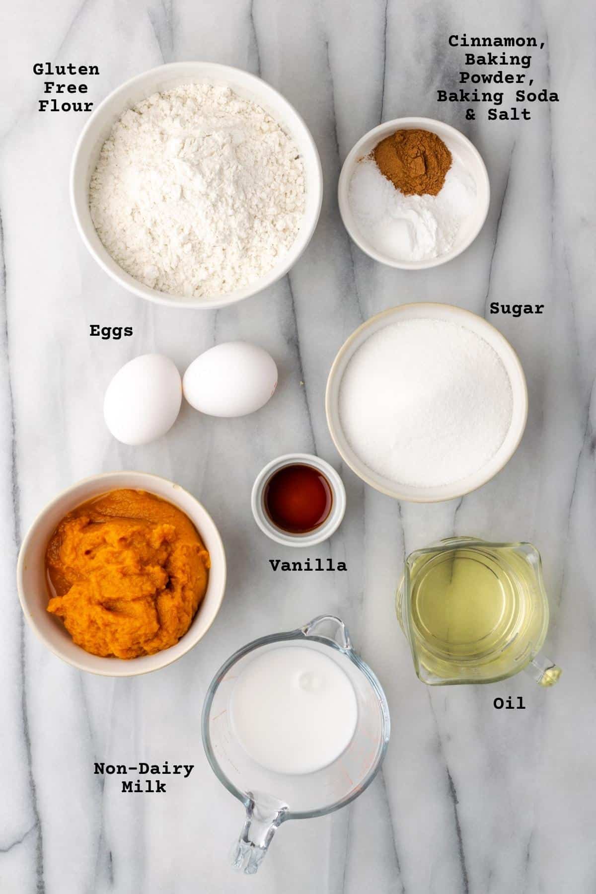 Ingredients for pumpkin bread on a white marble table.