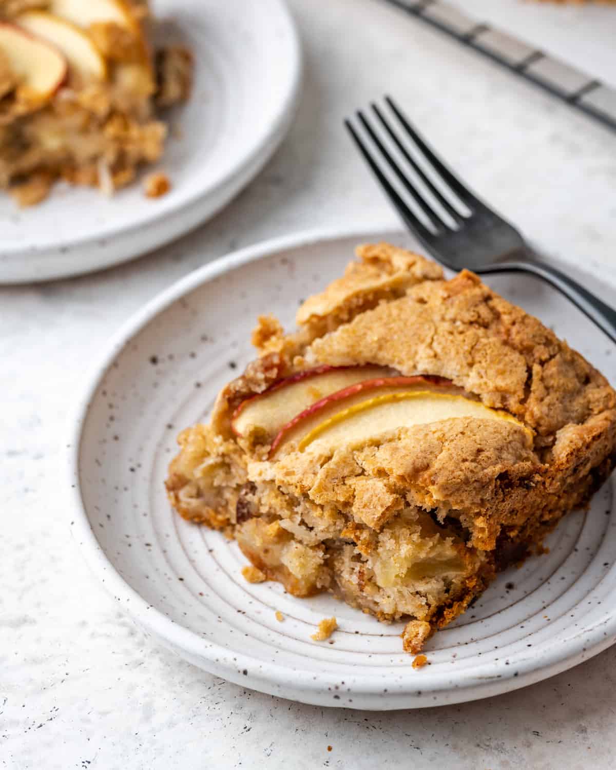 A slice of apple cake on a white plate.