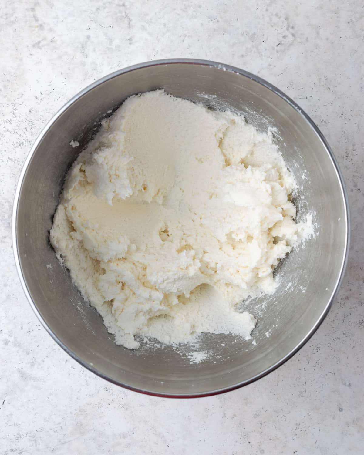 Butter and sugar being creamed together in a large metal mixing bowl.