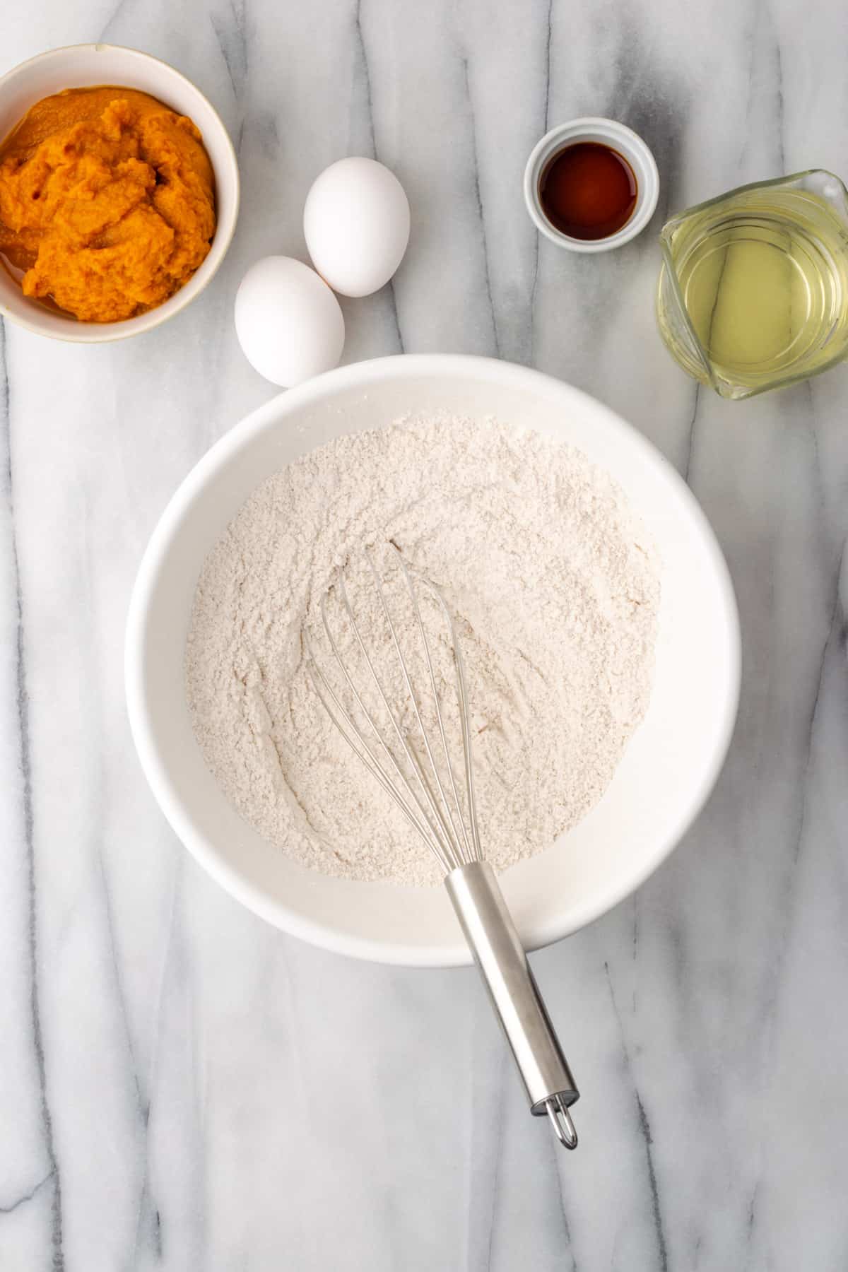 Dry ingredients being whisked in a large white bowl.