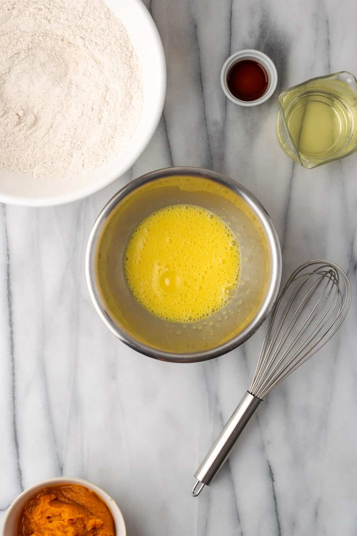 Eggs whisked to frothy bubbles in a small metal bowl.