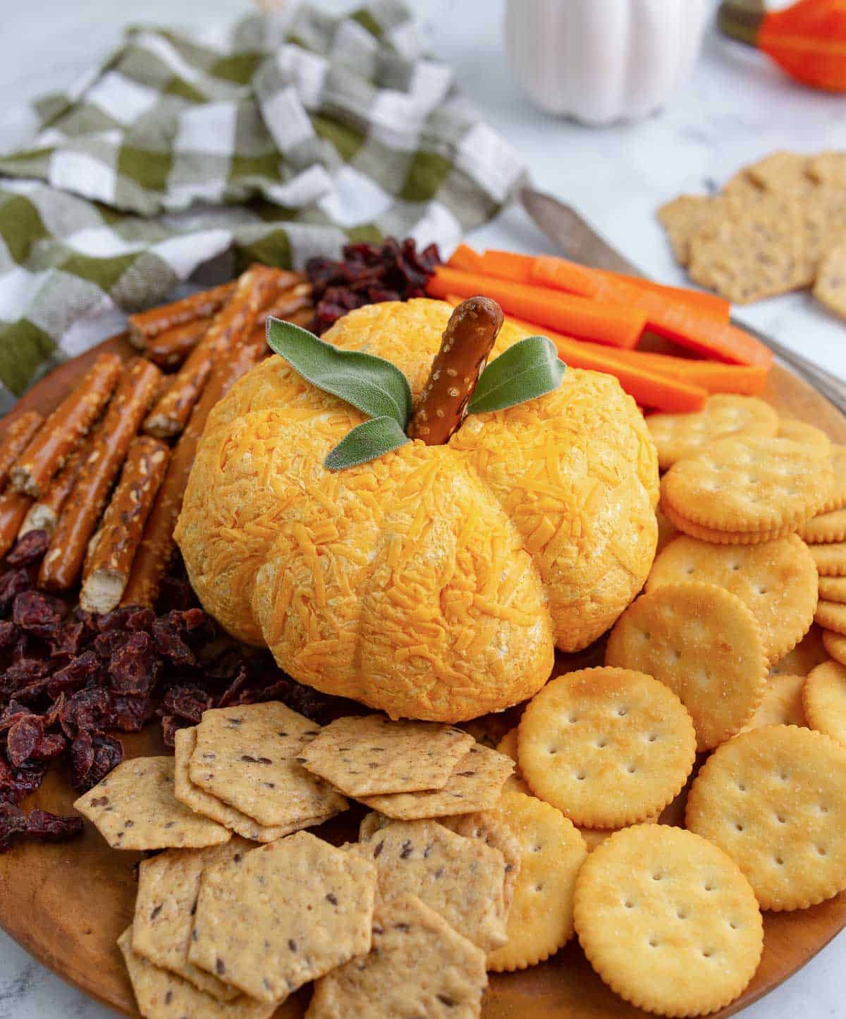 Pumpkin shaped cheese ball served with a plate of various crackers.