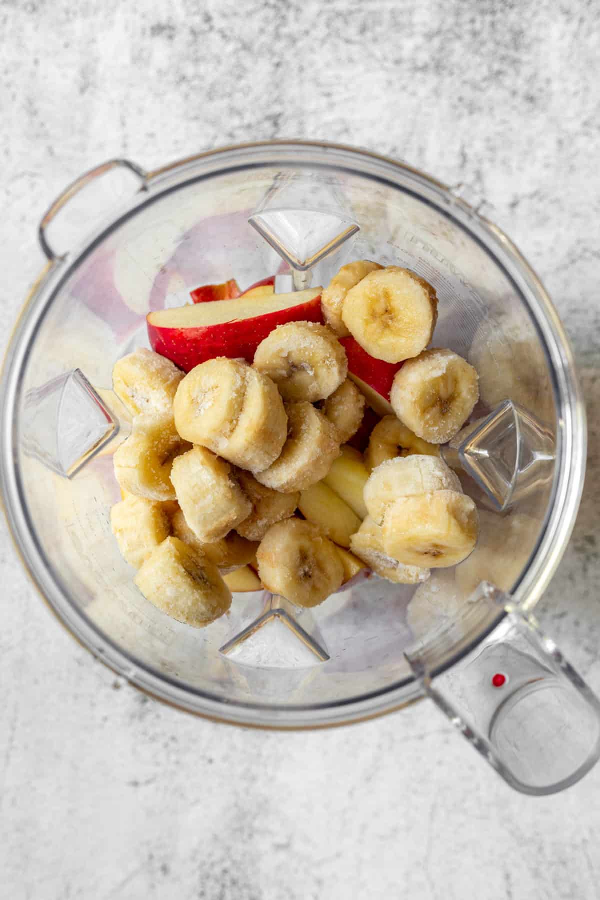 Apple slices and frozen banana slices in a blender.