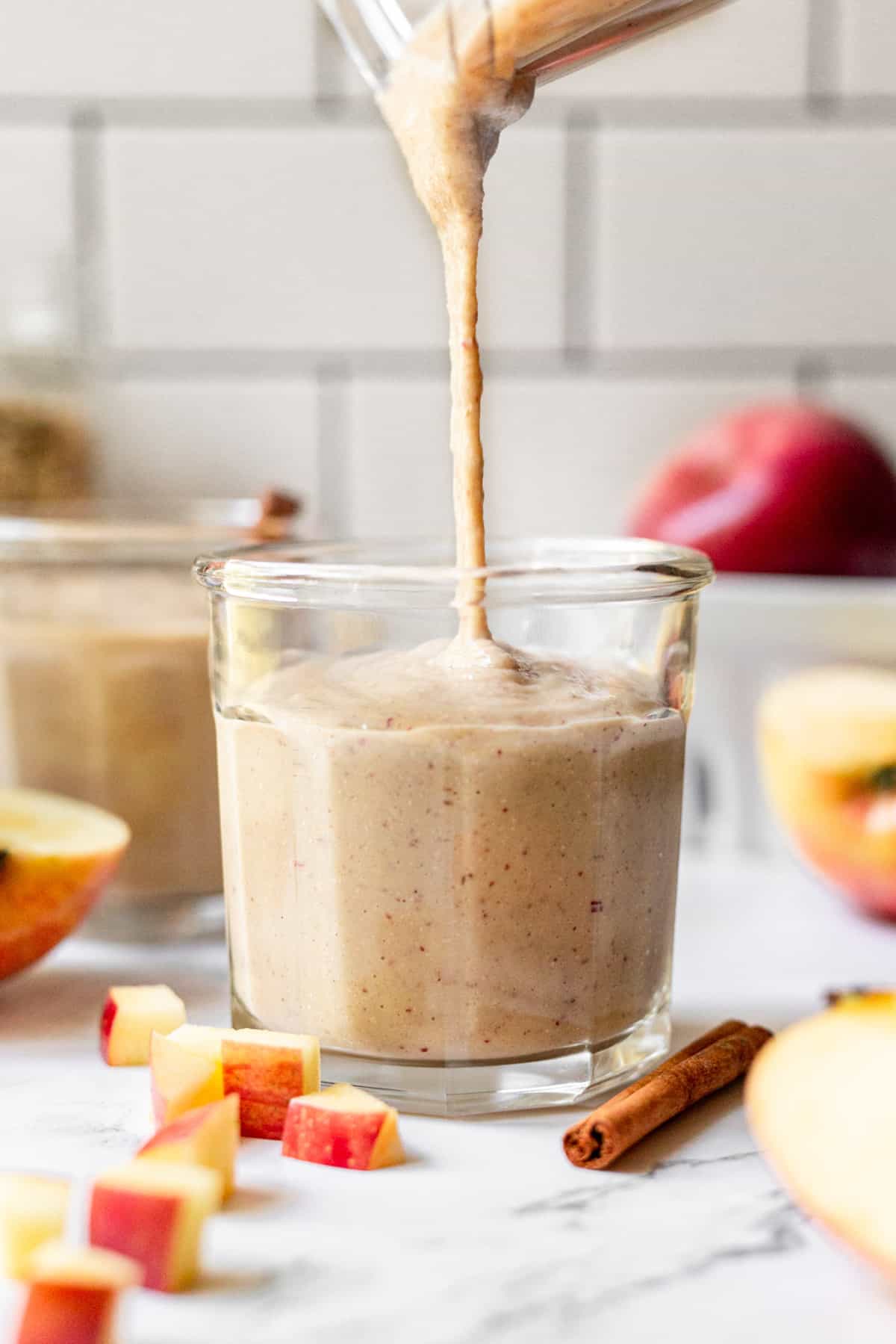 Apple smoothie being poured into a small glass.