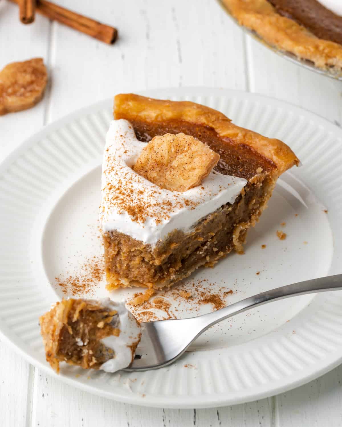 A slice of apple butter pie on a white plate with a bite on a fork.