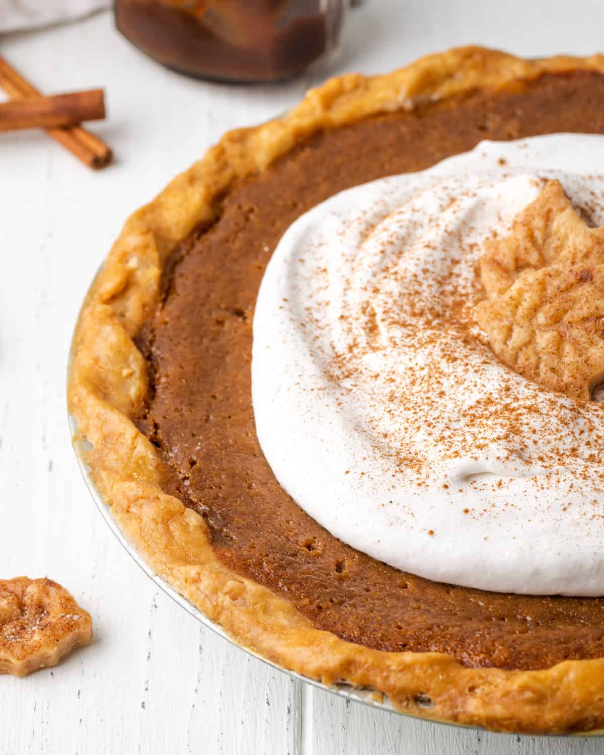 Closeup of a baked apple butter pie topped with whipped cream.