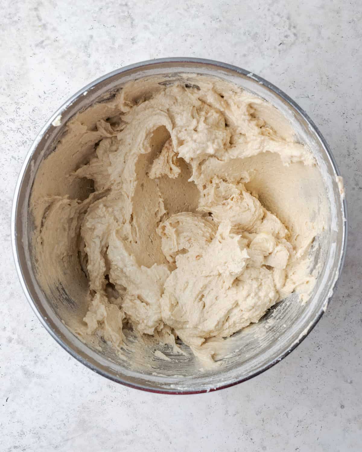 Partially mixed cake batter beaten in a metal mixing bowl.