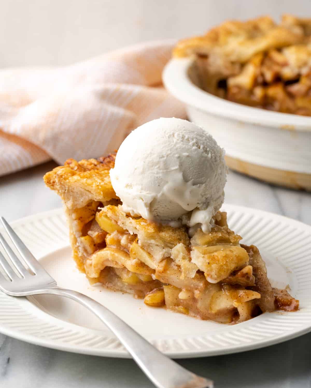 A slice of apple pear pie topped with a scoop of vanilla ice cream.