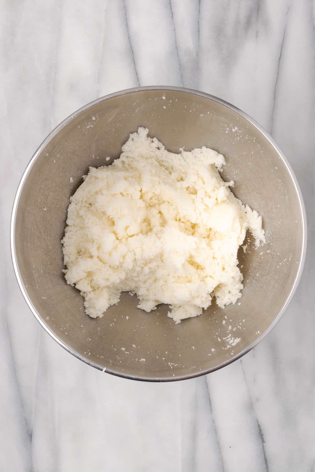 Butter and sugar creamed together in a large metal mixing bowl.